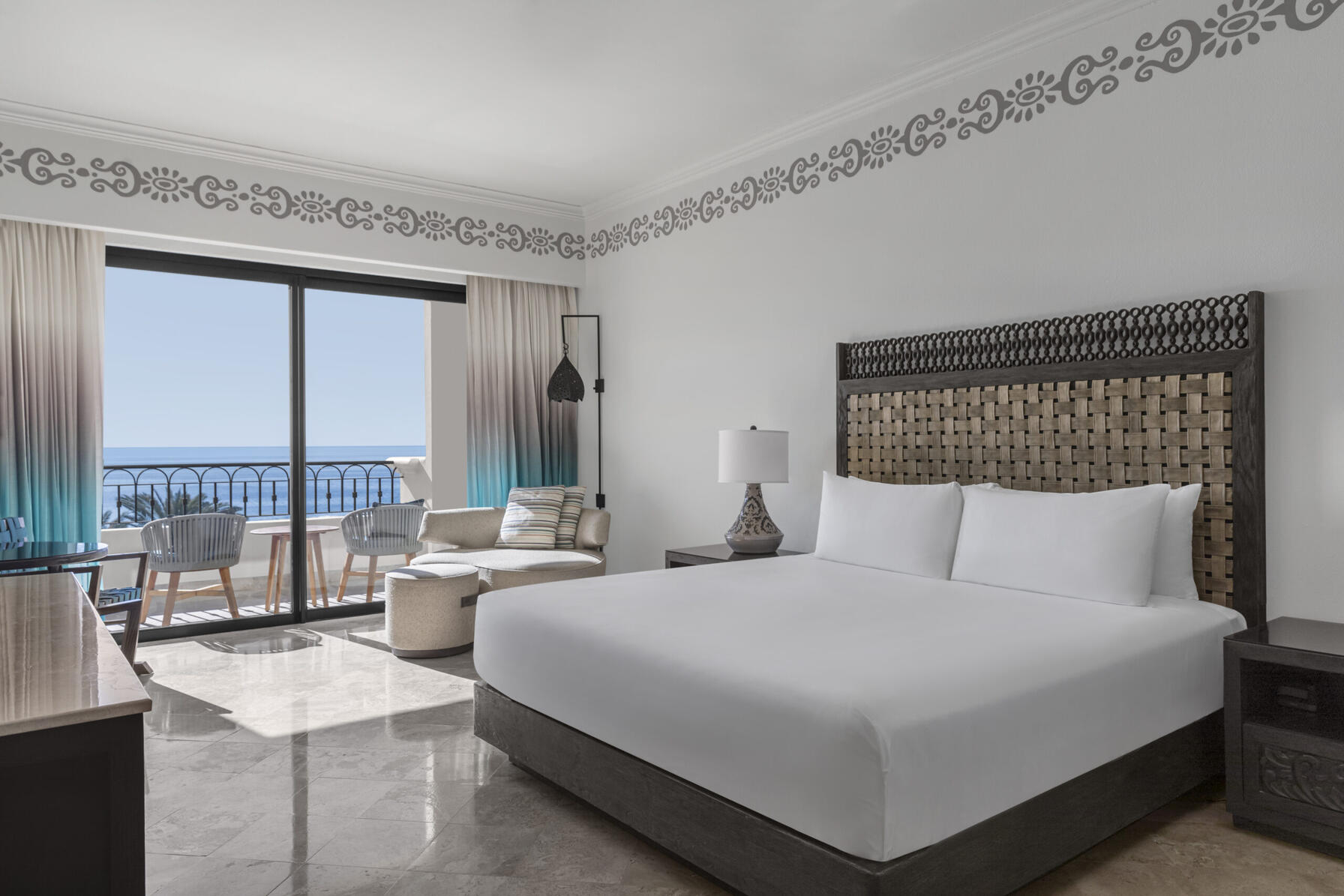 imagen de una habitación con cama doble, sala de estar y balcón con vista al mar
