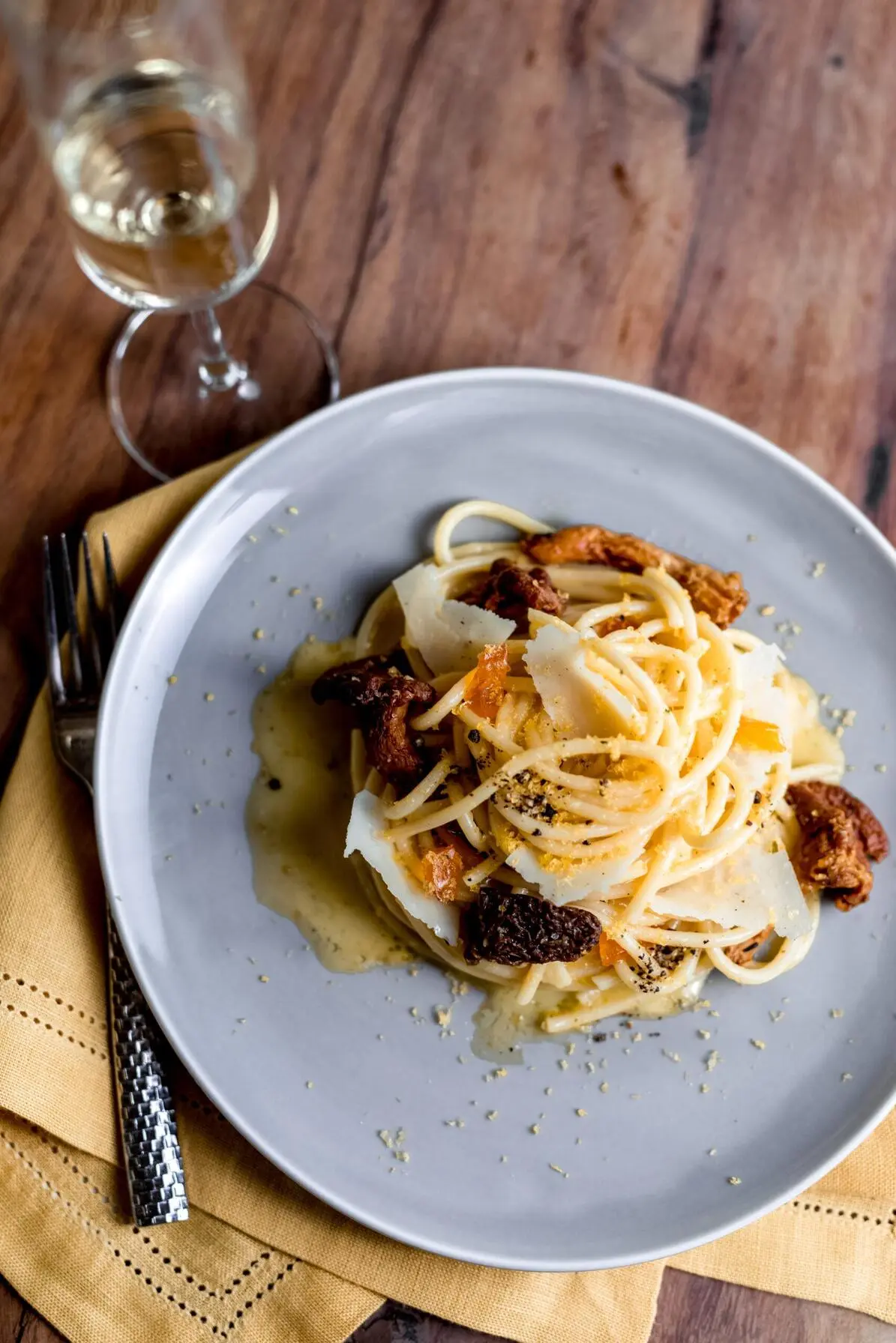 imagen de un espagueti en un plato con una copa de vino blanco