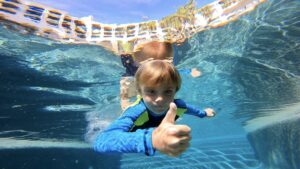 foto de un niño mostrando los pulgares hacia arriba desde un ángulo bajo dentro de las aguas