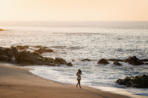 foto de una mujer en bikini blanco caminando por la playa del mar