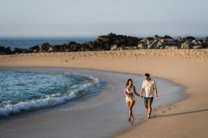 imagen de dos personas caminando en la playa del mar
