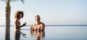 picture of two men holding drinks in infinity pool