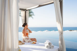 picture of a women sitting on the bench bed next to the pool with sea view