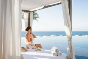 picture of a women sitting on the bench bed next to the pool with sea view