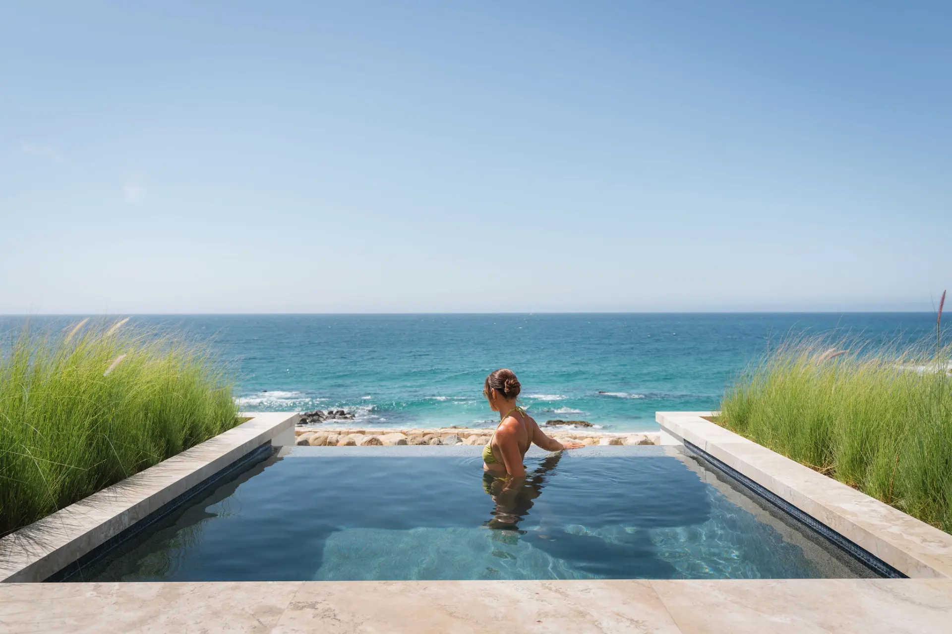 imagen de una mujer en una piscina con vista al mar