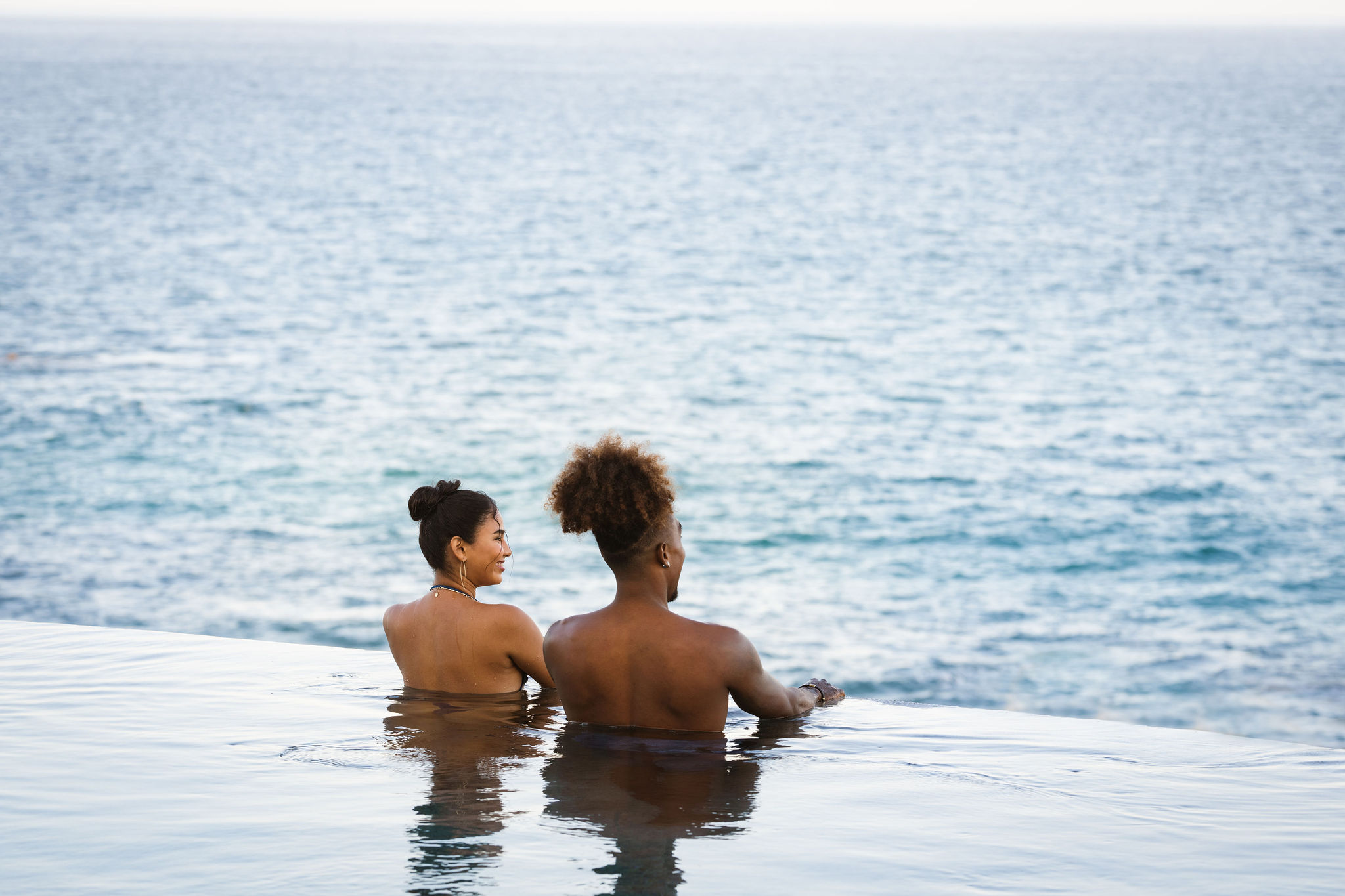 picture of two people in infinity pool with sea view