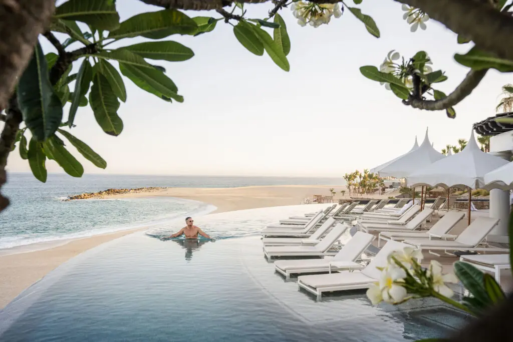 picture of a man in infinity pool with sea and beach view