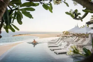 picture of a man in infinity pool with sea and beach view