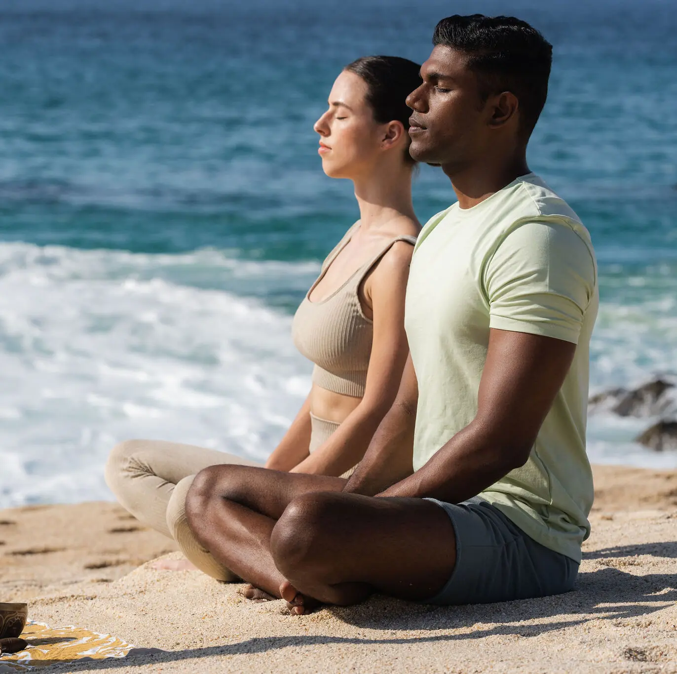 picture of a women and a man doing yoga on a sea beach