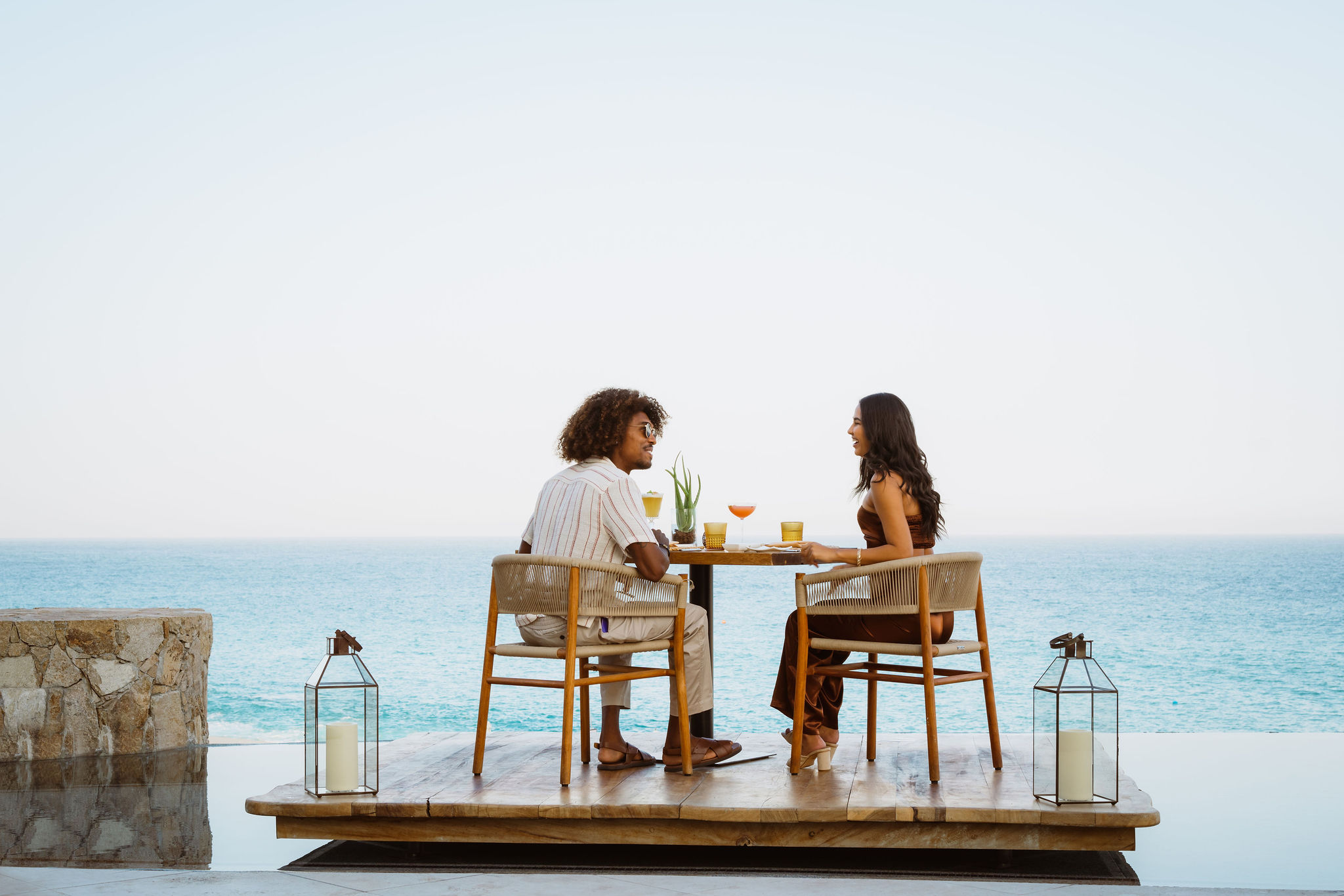 Imagen de dos personas sentadas en un restaurante abierto con vistas al mar.