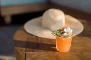 picture of a drink of orange colour with a white flower placed on top of it