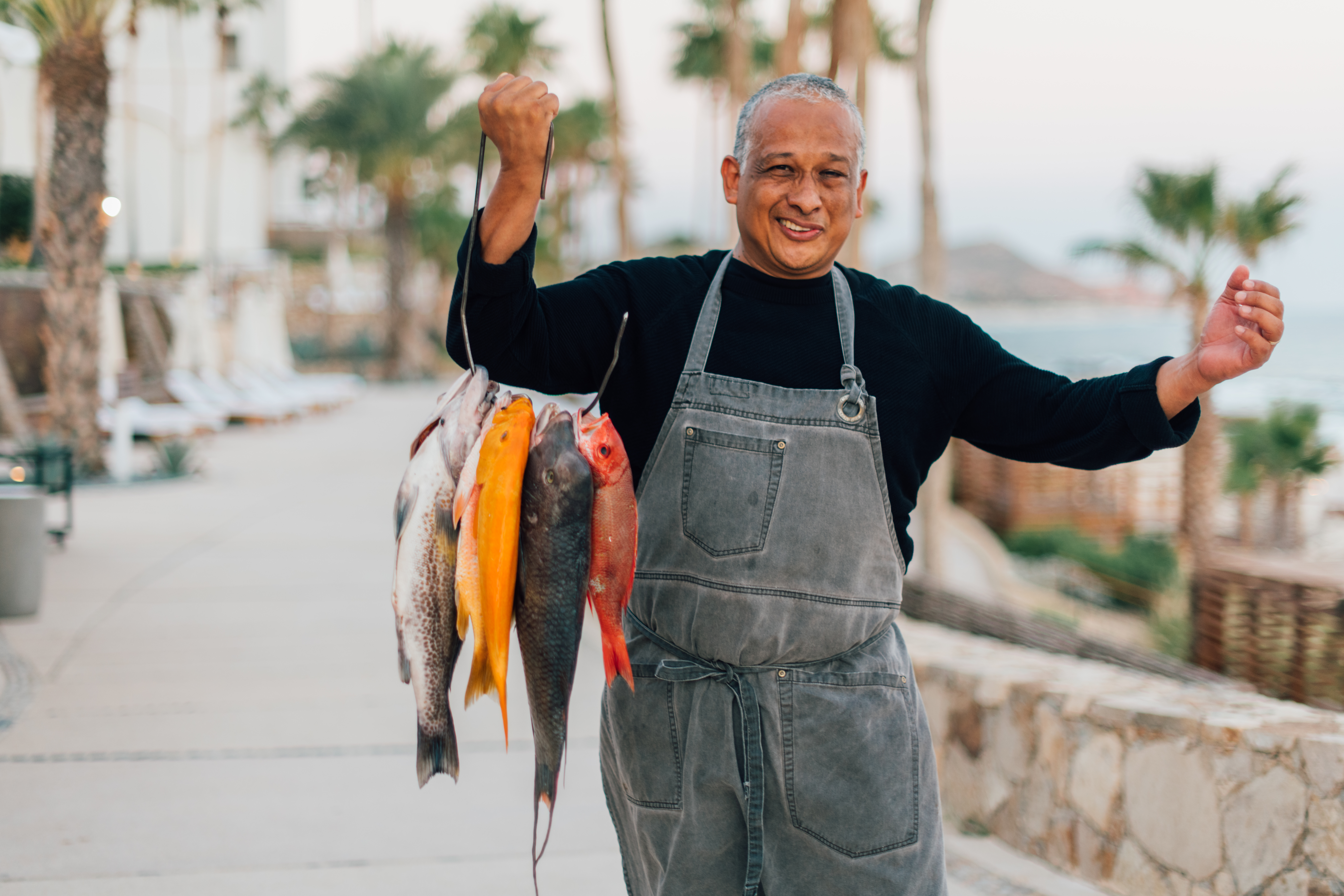 picture of a man carrying fishes in one hand