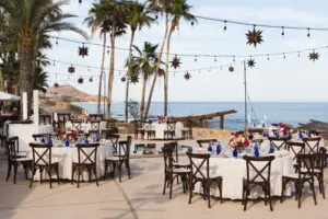 picture of an empty restaurant with glass on table and cushion chairs and sea view